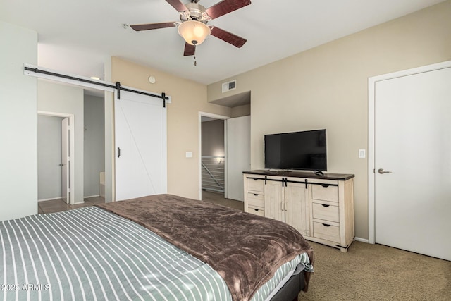 carpeted bedroom featuring a barn door and ceiling fan