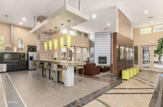 kitchen featuring stainless steel appliances, a breakfast bar, pendant lighting, and a towering ceiling