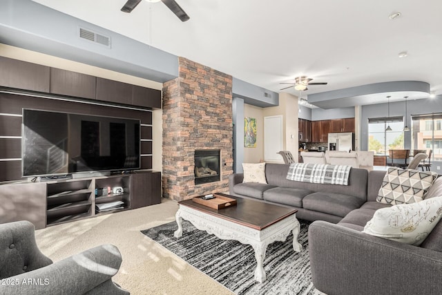 carpeted living room featuring a fireplace and ceiling fan