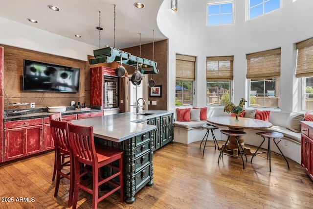 kitchen featuring a sink, a towering ceiling, dark brown cabinets, light wood finished floors, and breakfast area