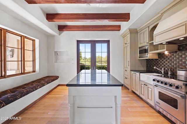 kitchen with dark countertops, decorative backsplash, cream cabinets, appliances with stainless steel finishes, and a kitchen island