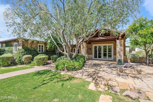 back of property with french doors, a lawn, and stucco siding