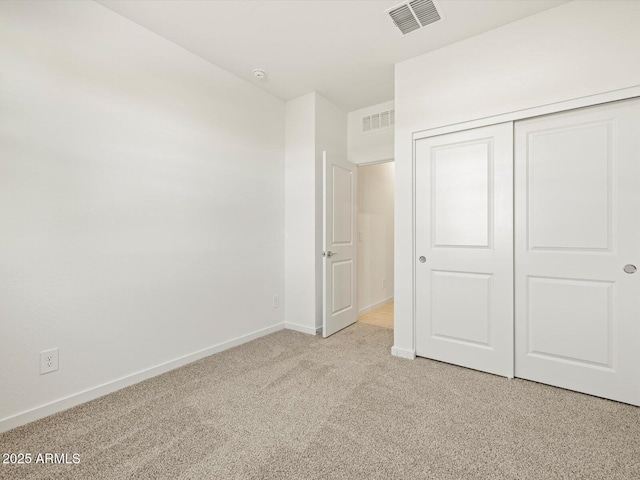 unfurnished bedroom with a closet, visible vents, light carpet, and baseboards