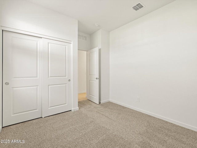 unfurnished bedroom with baseboards, visible vents, a closet, and light colored carpet