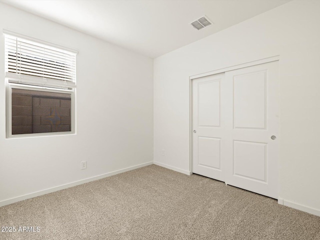 unfurnished bedroom featuring a closet, light colored carpet, visible vents, and baseboards