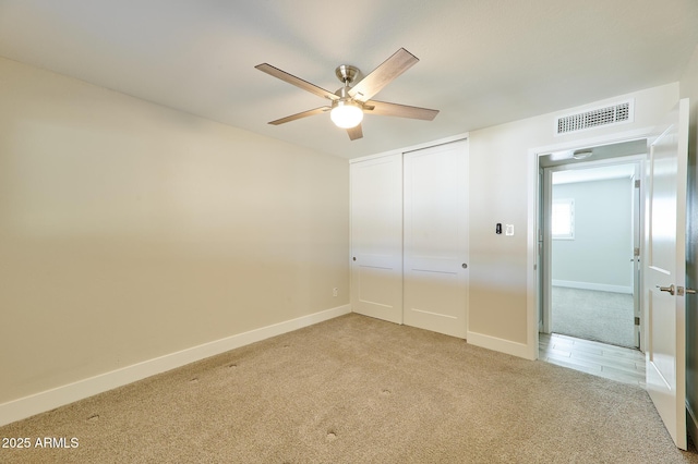 unfurnished bedroom with ceiling fan, light colored carpet, and a closet