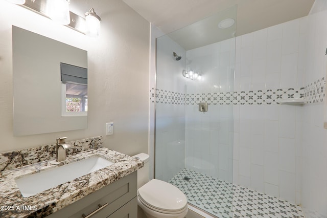 bathroom featuring vanity, toilet, and a tile shower