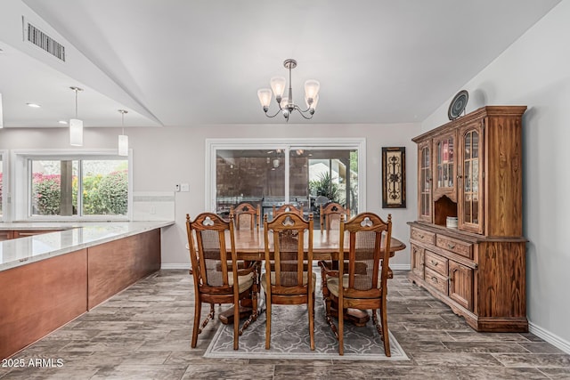 dining area featuring a chandelier, baseboards, lofted ceiling, dark wood-type flooring, and visible vents