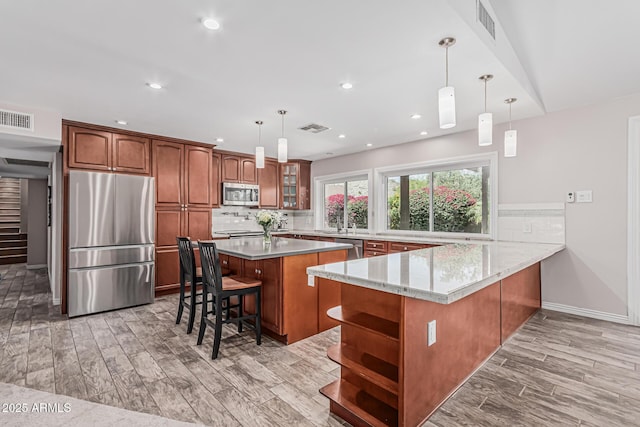 kitchen with visible vents, open shelves, appliances with stainless steel finishes, and a breakfast bar area