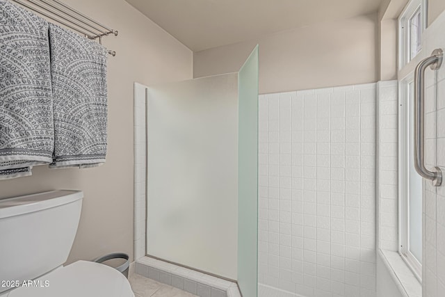 full bathroom featuring tile patterned flooring, toilet, and tiled shower