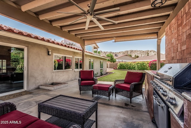 view of patio with grilling area, an outdoor hangout area, a ceiling fan, exterior kitchen, and a mountain view