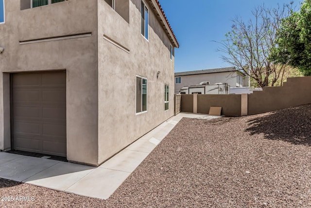 view of home's exterior with fence, stucco siding, and an attached garage