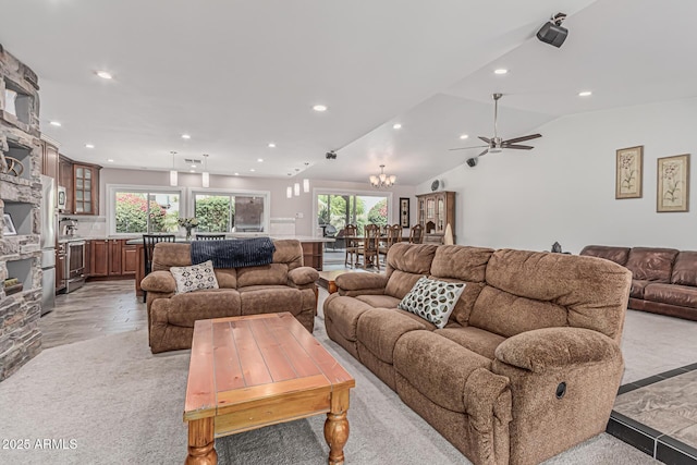 living room with a healthy amount of sunlight, vaulted ceiling, ceiling fan with notable chandelier, and recessed lighting