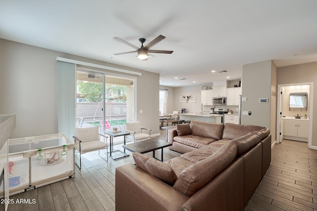 living room featuring ceiling fan, sink, and light hardwood / wood-style floors