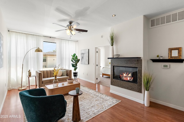 6900 E Princess Dr Unit 2247, Phoenix, AZ 85054 - living room featuring a ceiling fan, wood finished floors, a multi sided fireplace, and baseboards