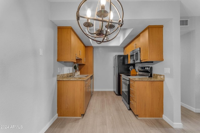 kitchen with light stone countertops, appliances with stainless steel finishes, sink, a notable chandelier, and light hardwood / wood-style floors