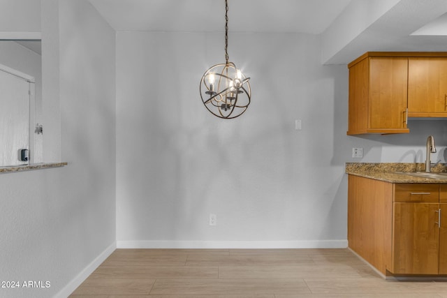 unfurnished dining area with a chandelier, sink, and light hardwood / wood-style flooring