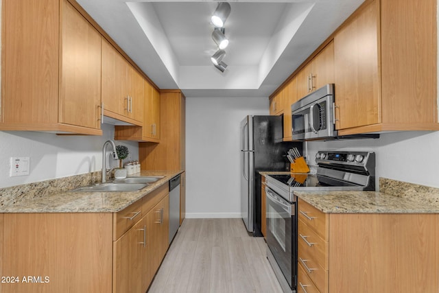 kitchen featuring track lighting, sink, light hardwood / wood-style flooring, light stone countertops, and appliances with stainless steel finishes