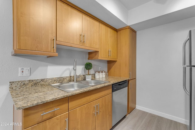 kitchen featuring light stone counters, sink, stainless steel appliances, and light hardwood / wood-style floors