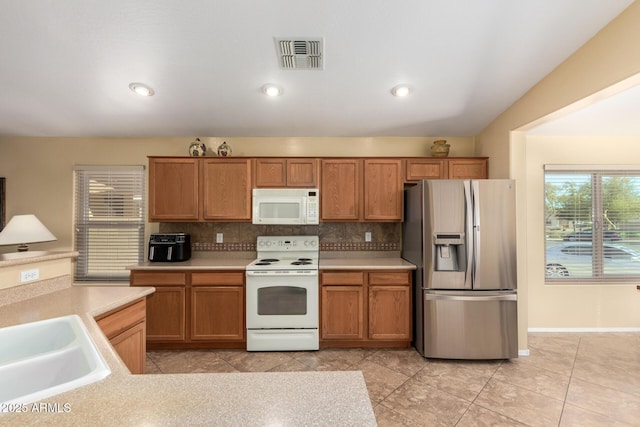 kitchen with sink, white appliances, and backsplash