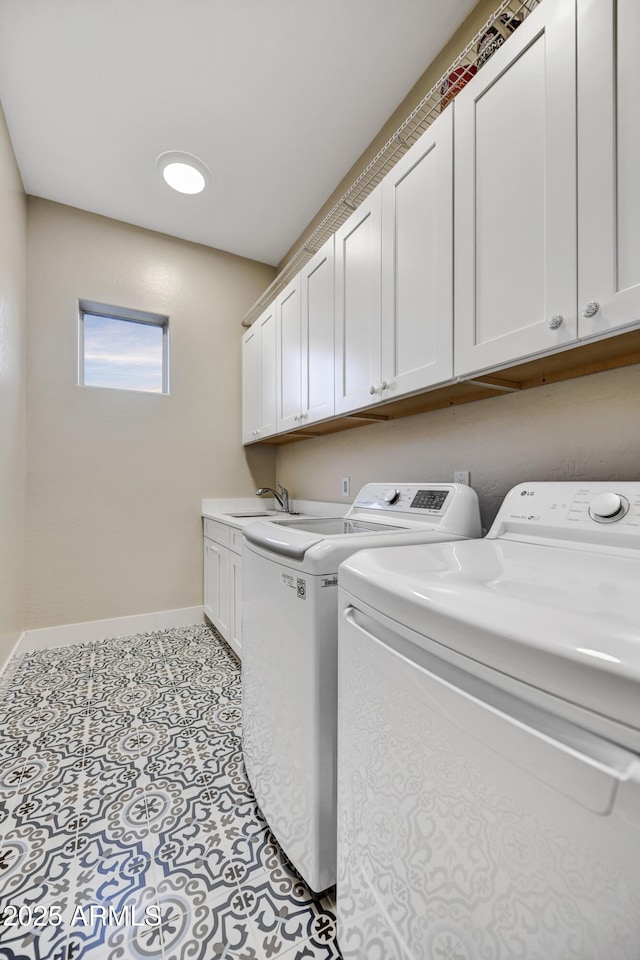 clothes washing area featuring a sink, baseboards, cabinet space, and washing machine and clothes dryer