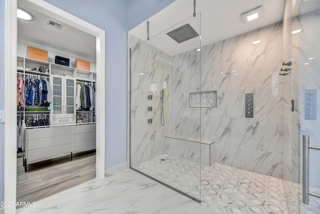 full bathroom featuring a marble finish shower, marble finish floor, a spacious closet, and visible vents