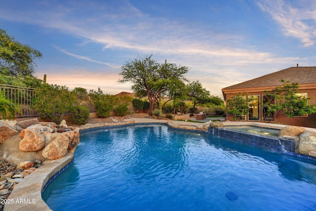 pool with a fenced backyard and an in ground hot tub
