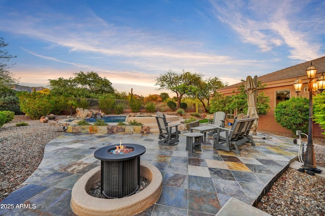 patio terrace at dusk with a fire pit and an outdoor pool