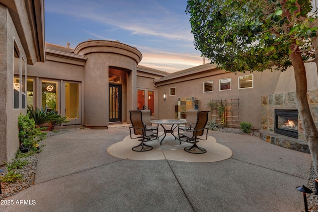 view of patio with a glass covered fireplace and outdoor dining space