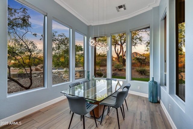 sunroom with crown molding, baseboards, visible vents, and wood finished floors