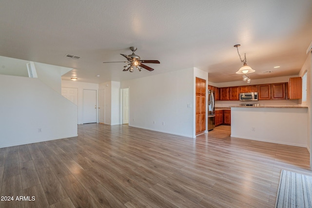 unfurnished living room featuring ceiling fan, a textured ceiling, and light hardwood / wood-style floors