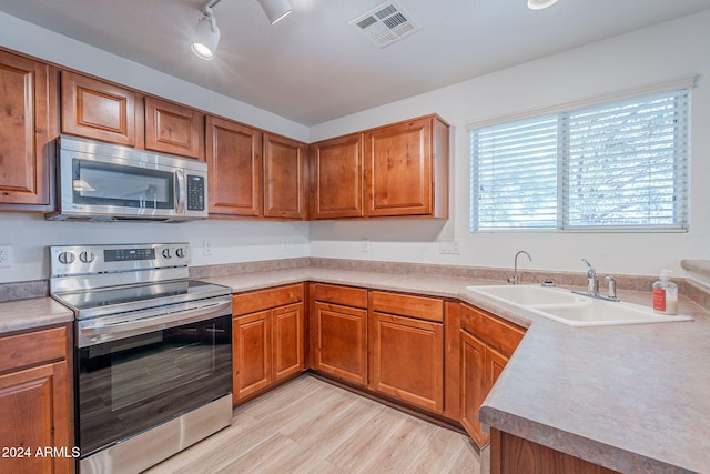 kitchen with appliances with stainless steel finishes, light hardwood / wood-style floors, and sink