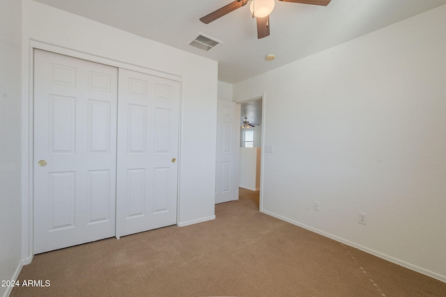 unfurnished bedroom with ceiling fan, light colored carpet, and a closet