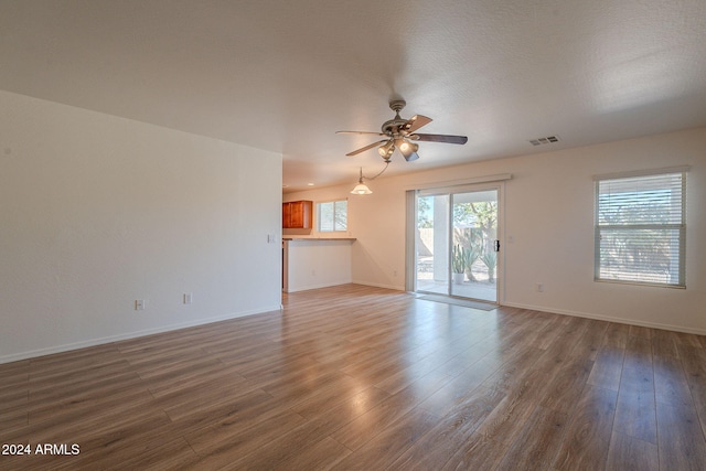 unfurnished living room featuring wood-type flooring, ceiling fan, and a textured ceiling