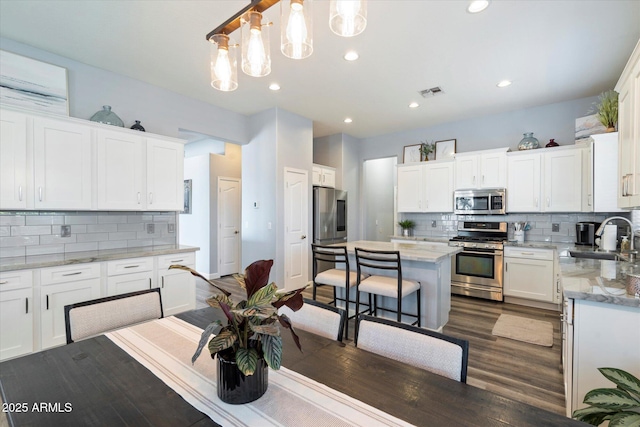 kitchen with sink, appliances with stainless steel finishes, white cabinetry, a center island, and decorative light fixtures