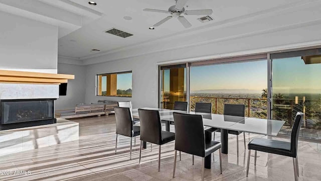 dining room with ceiling fan, plenty of natural light, and a tiled fireplace