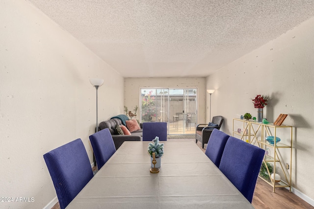 dining room featuring wood-type flooring and a textured ceiling