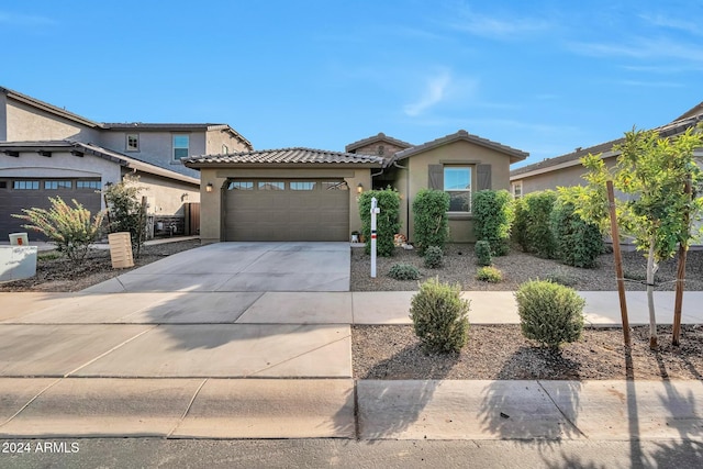 view of front of property featuring a garage, concrete driveway, a tile roof, and stucco siding