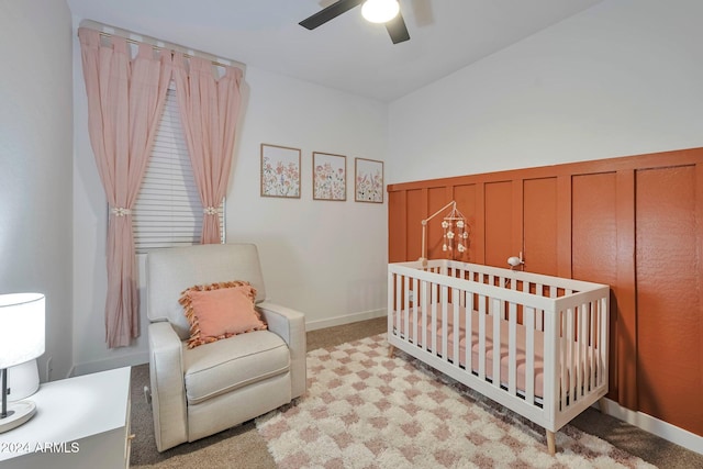 bedroom with a ceiling fan, a nursery area, and carpet flooring