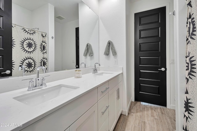 full bath featuring double vanity, a sink, visible vents, and wood tiled floor