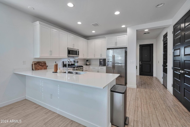 kitchen with stainless steel appliances, light countertops, light wood-type flooring, and visible vents