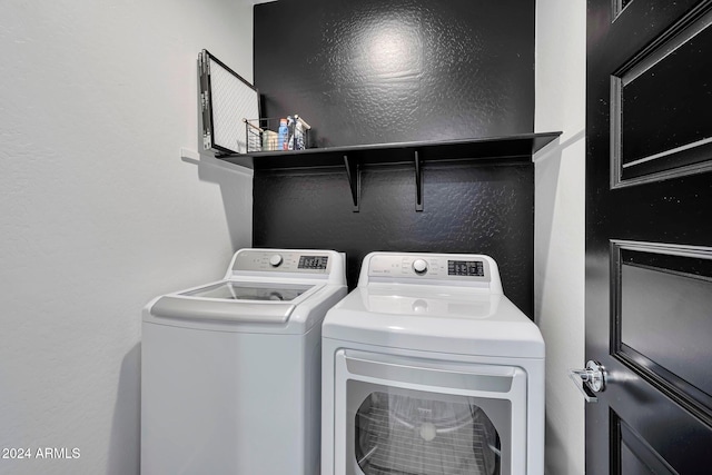 washroom with a textured wall, laundry area, and independent washer and dryer