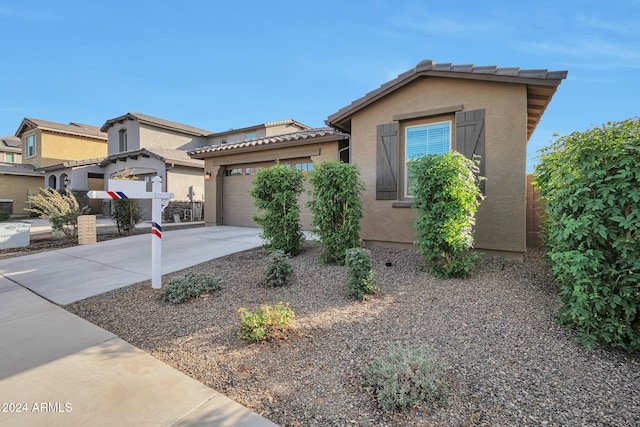 view of front of house with a garage, a tile roof, concrete driveway, and stucco siding