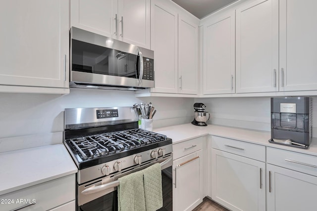 kitchen featuring stainless steel appliances, light countertops, and white cabinetry