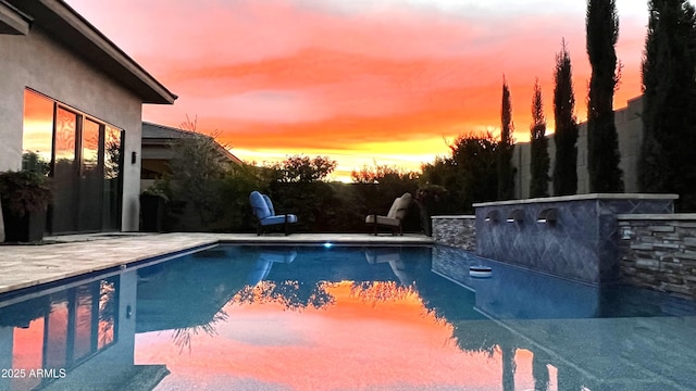 pool at dusk featuring a patio