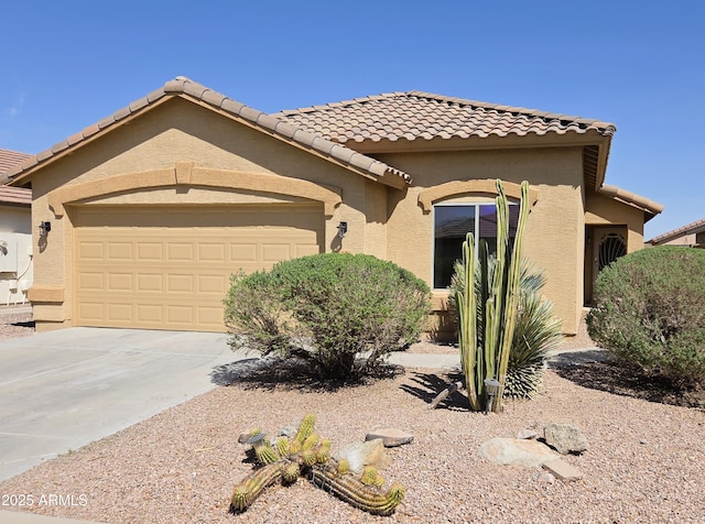 mediterranean / spanish-style house featuring a tile roof, concrete driveway, stucco siding, and an attached garage