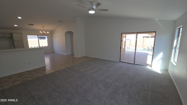 tiled empty room featuring visible vents, arched walkways, ceiling fan with notable chandelier, carpet floors, and vaulted ceiling
