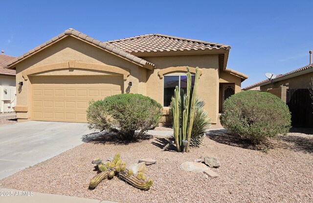 mediterranean / spanish-style home featuring an attached garage, a tile roof, and stucco siding