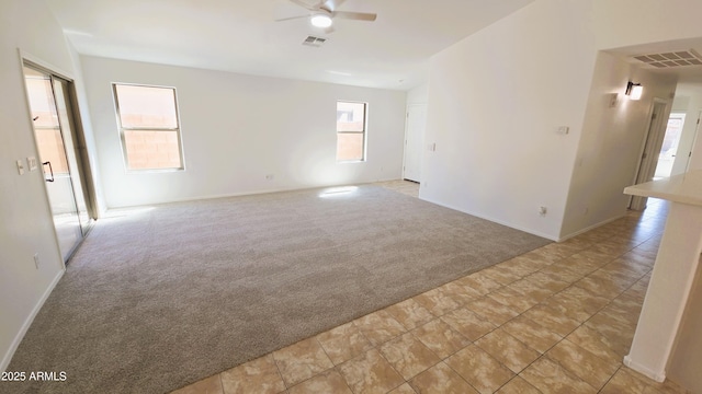 unfurnished room with light colored carpet, visible vents, ceiling fan, and baseboards