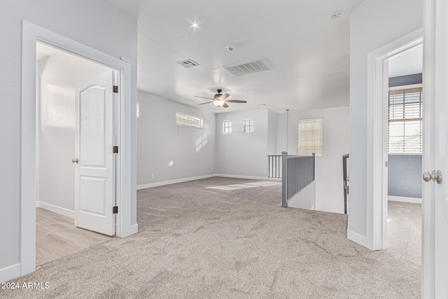 empty room featuring ceiling fan and light colored carpet